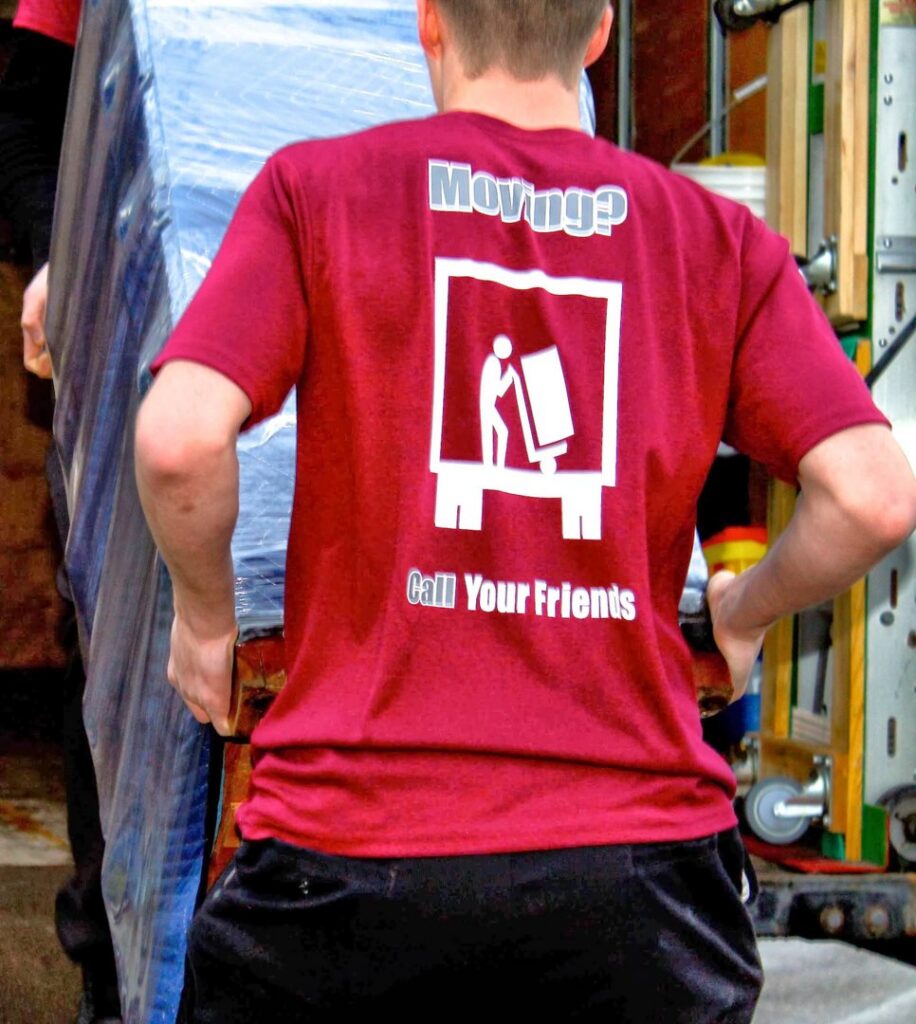 A mover from Your Friends - Moving Services loading a wrapped item into a moving truck in Lansing, MI.
