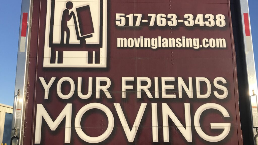 The back of a Your Friends - Moving Services truck showing branding and contact information in Lansing, MI.