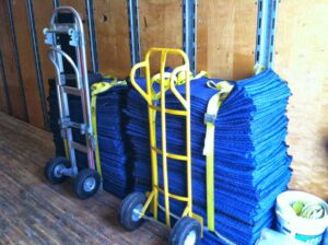 Hand trucks and stacks of blue moving blankets inside a Your Friends - Moving Services truck in Lansing, MI.