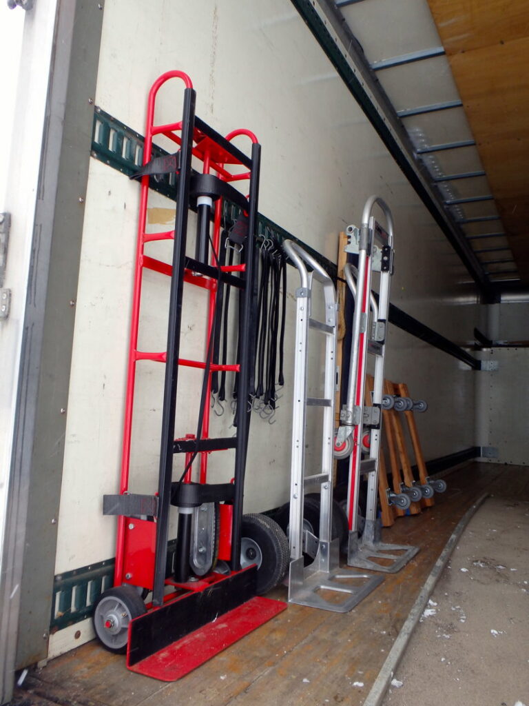 Various hand trucks and moving equipment stored inside a Your Friends - Moving Services truck in Lansing, MI.